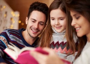 Parents reading bible to their daughter